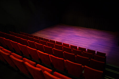 afbeelding van een theaterzaal met rode stoelen